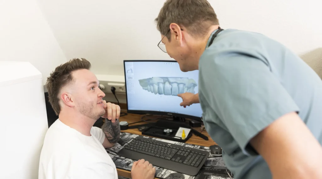 Zwei Zahnärzte analysieren eine 3D-Röntgenaufnahme am Bildschirm